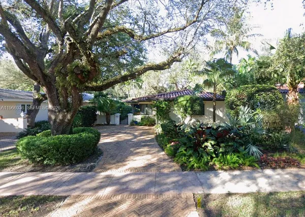 a view of a street with potted plants and large trees