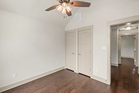 an empty room with wooden floor fan and windows