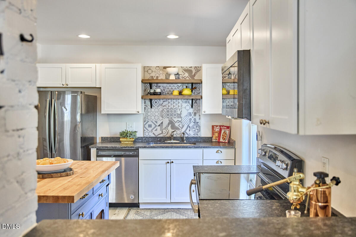 214 Moline Street Durham, NC 27707 - Photo 13 of 49 a kitchen with kitchen island granite countertop wooden cabinets and a refrigerator