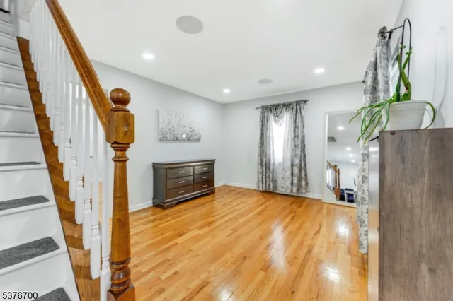 a view of an empty room with wooden floor and staircase
