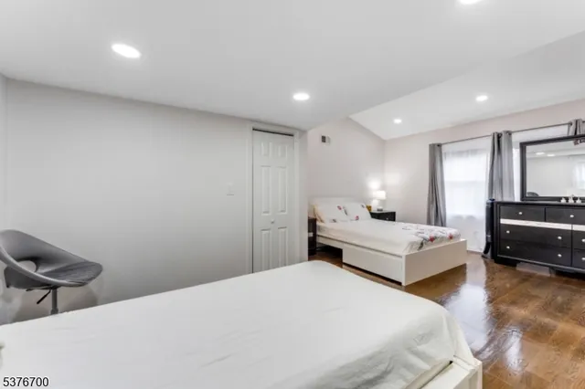 a bedroom with a bed window and walk in closet with wooden floor