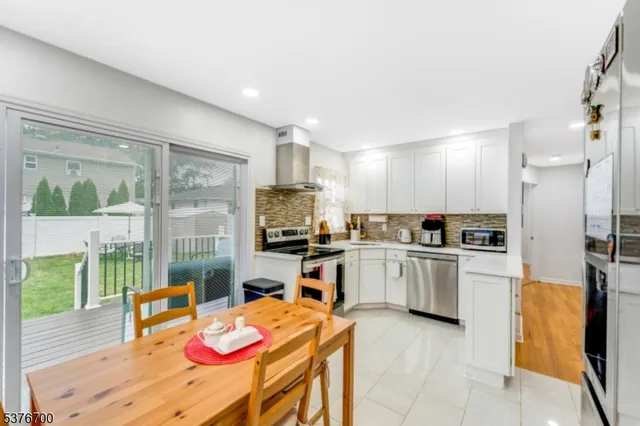 a kitchen with a refrigerator a stove top oven a sink a dining table and chairs