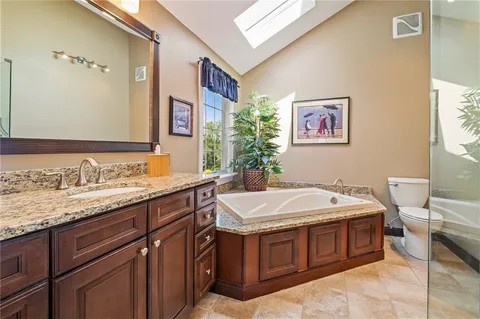 a spacious bathroom with a granite countertop double vanity sink and a bathtub