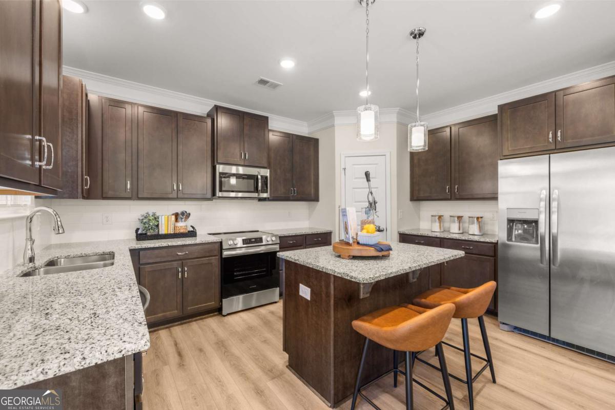 234 Shantz Way, Unit (LOT A34) Byron, GA 31008 - Photo 8 of 23 a kitchen with stainless steel appliances granite countertop a kitchen island hardwood floor sink stove dining table and chairs