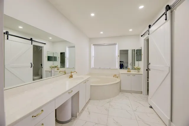 a large white bathroom with a large mirror vanity shower and bathtub