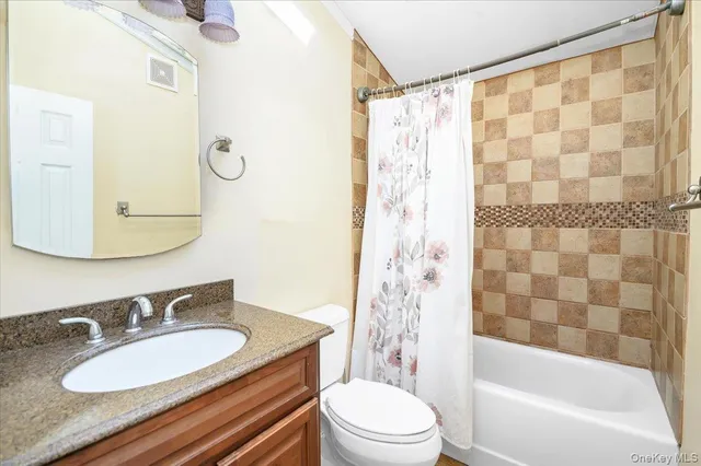 a bathroom with a granite countertop sink toilet a mirror a bathtub and shower