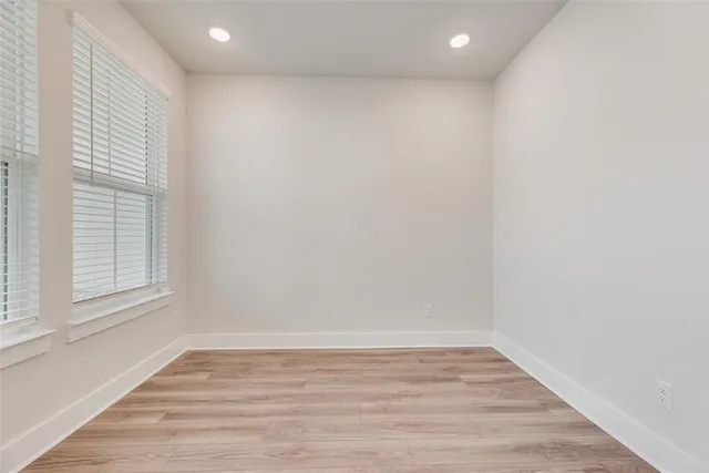 a view of a hallway with wooden floor and a kitchen space