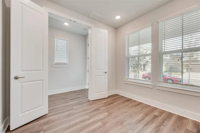 a view of empty room with wooden floor and fan