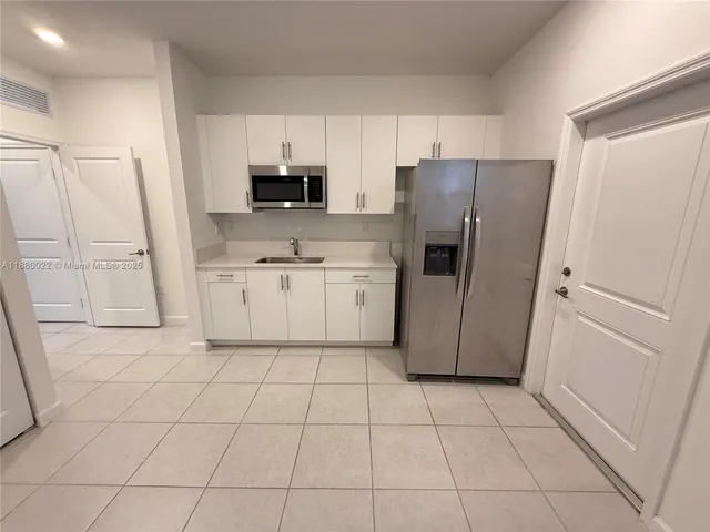 a kitchen with white cabinets and refrigerator