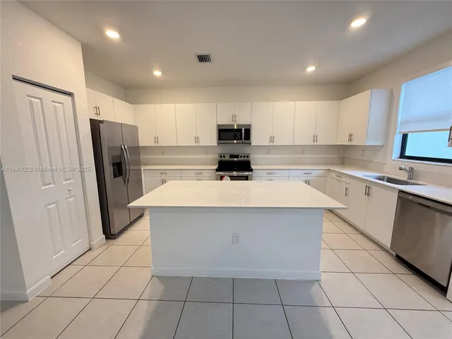 a kitchen with a sink a refrigerator and cabinets