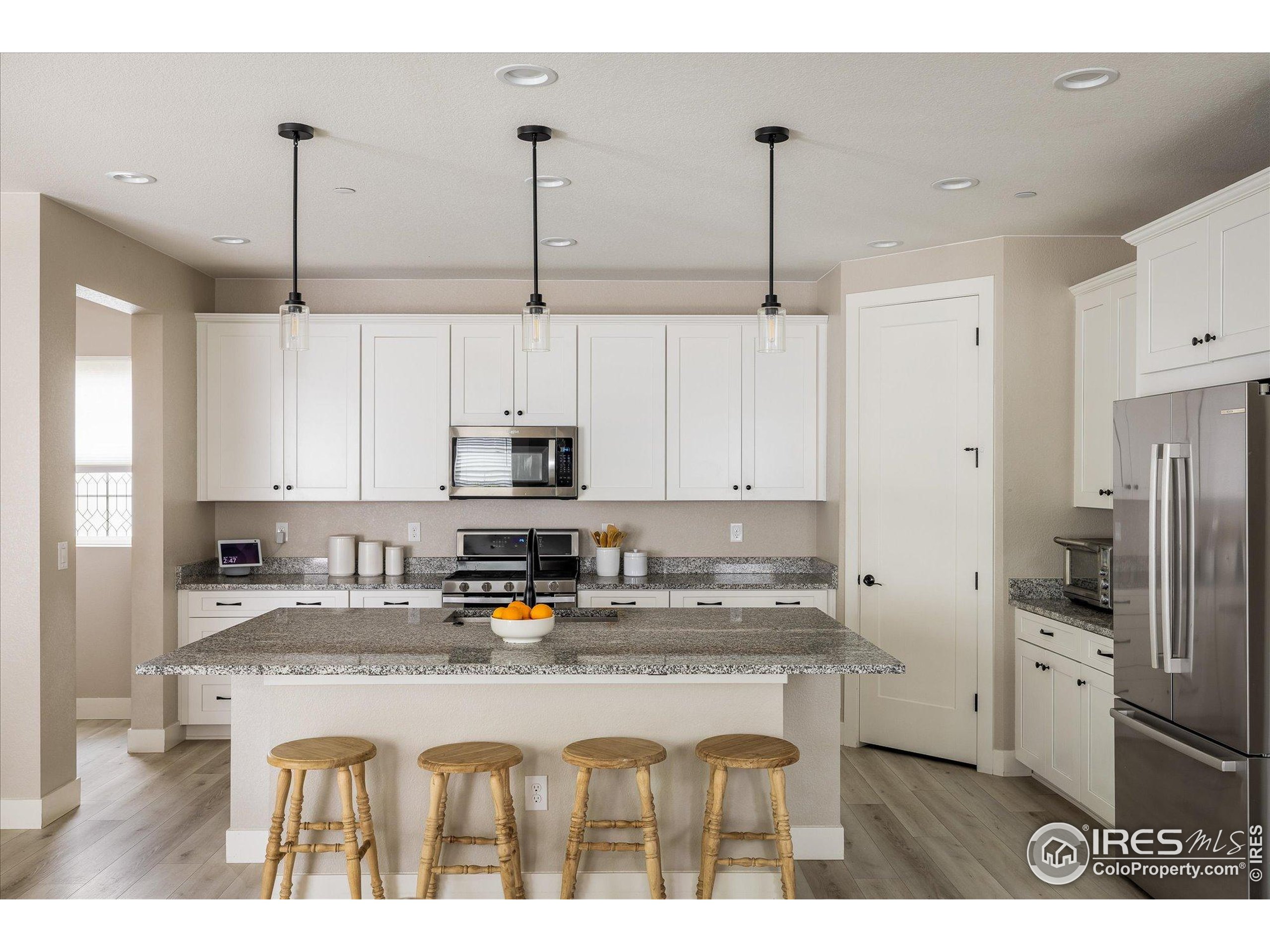 10121 Flower Street Westminster, CO 80021 - Photo 13 of 40 a kitchen with stainless steel appliances granite countertop a sink a refrigerator a stove a kitchen island and cabinets
