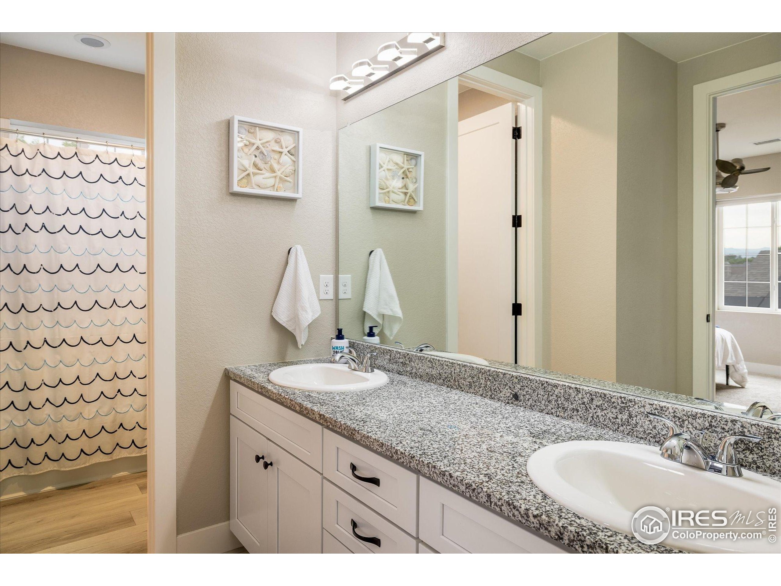 10121 Flower Street Westminster, CO 80021 - Photo 26 of 40 a bathroom with a granite countertop sink a mirror a vanity and a shower