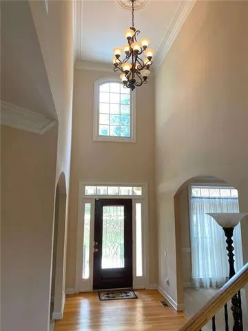 a view of a hallway with wooden floor and a chandelier