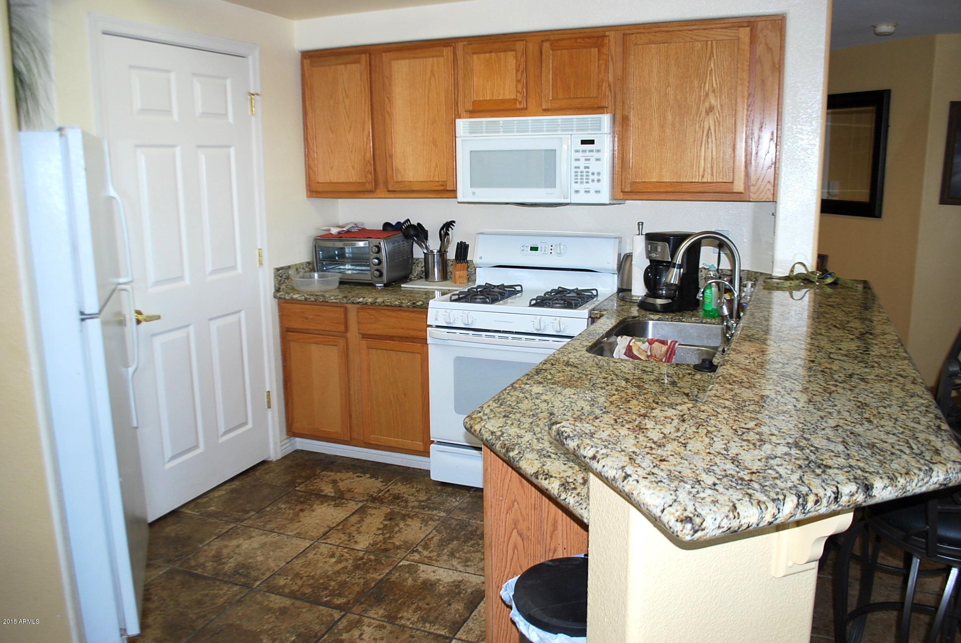 10030 West Indian School Road, Unit 158 Phoenix, AZ 85037 - Photo 6 of 28 a kitchen with a sink a stove and cabinets