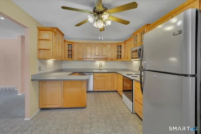 a kitchen with stainless steel appliances granite countertop a refrigerator a sink dishwasher a stove with white cabinets and a granite counter top