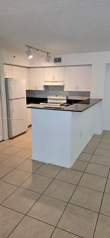 a kitchen with a refrigerator and white cabinets