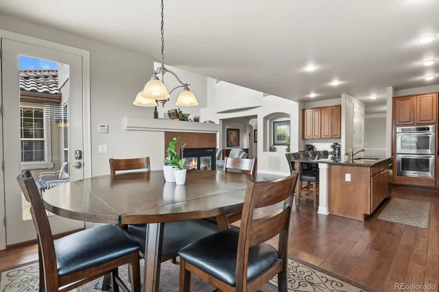 a dining room with wooden floor a chandelier a wooden table and chairs