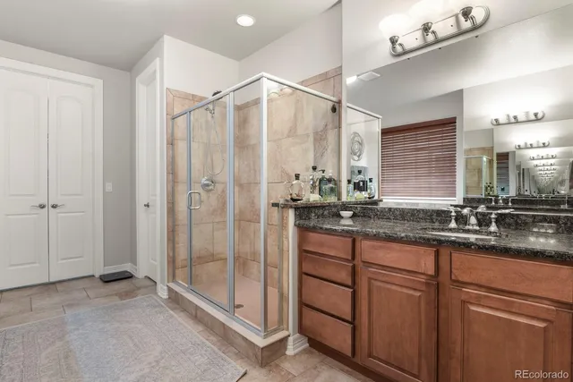 a bathroom with a granite countertop sink a mirror and shower
