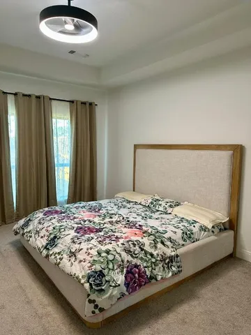 a bed sitting in a bedroom next to a window and cabinet