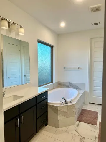 a bathroom with a tub sink and mirror