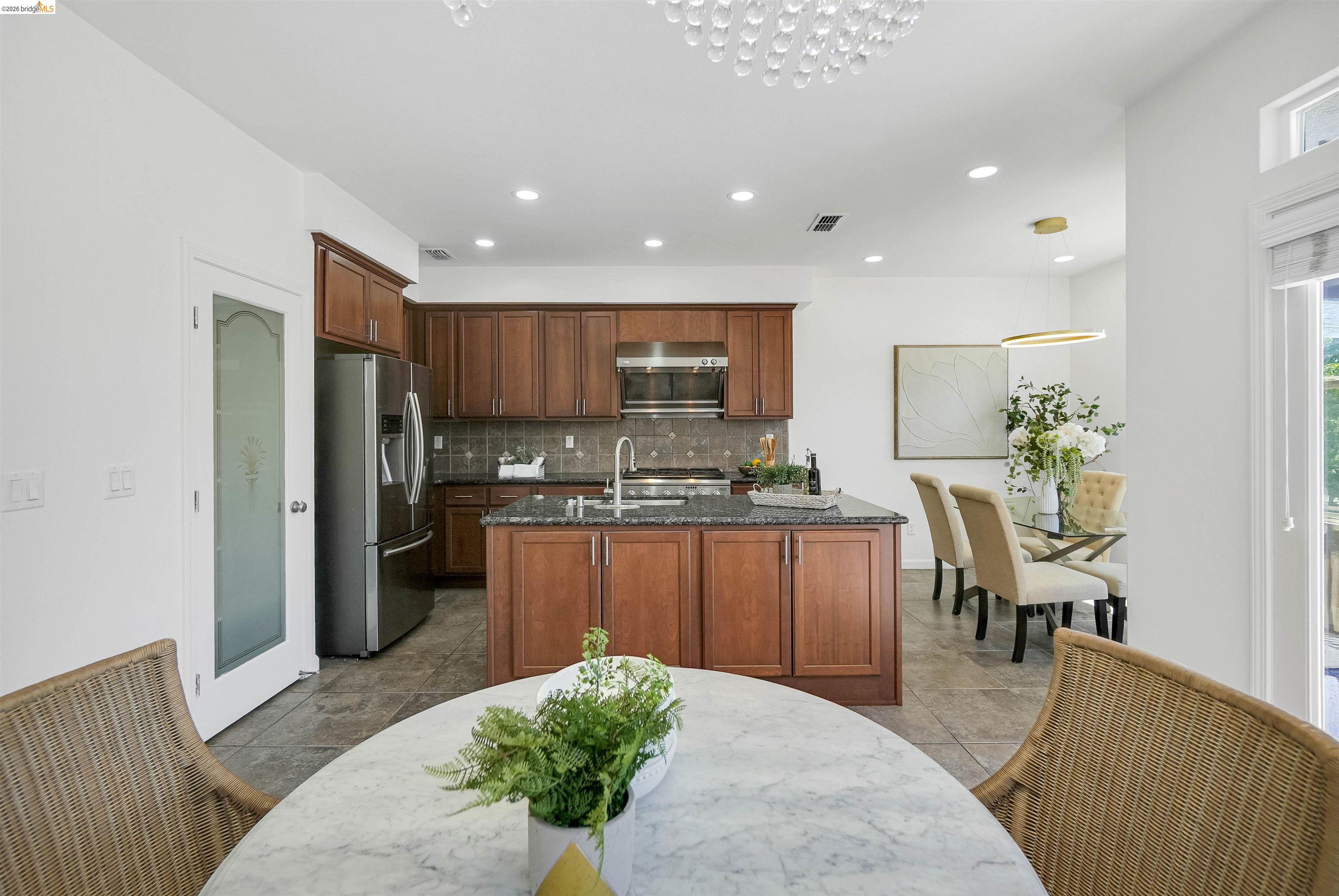 449 Constantine Court San Ramon, CA 94583 - Photo 20 of 63 Open-concept kitchen featuring wood cabinetry, dark stone countertops, stainless steel appliances, and tile flooring