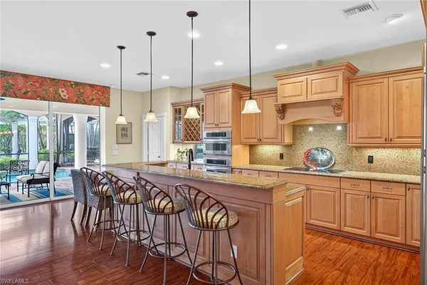 a kitchen with stainless steel appliances granite countertop a stove a sink and white cabinets with wooden floors