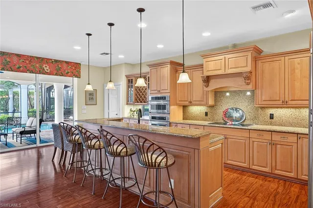 a kitchen with stainless steel appliances granite countertop a stove a sink and white cabinets with wooden floors