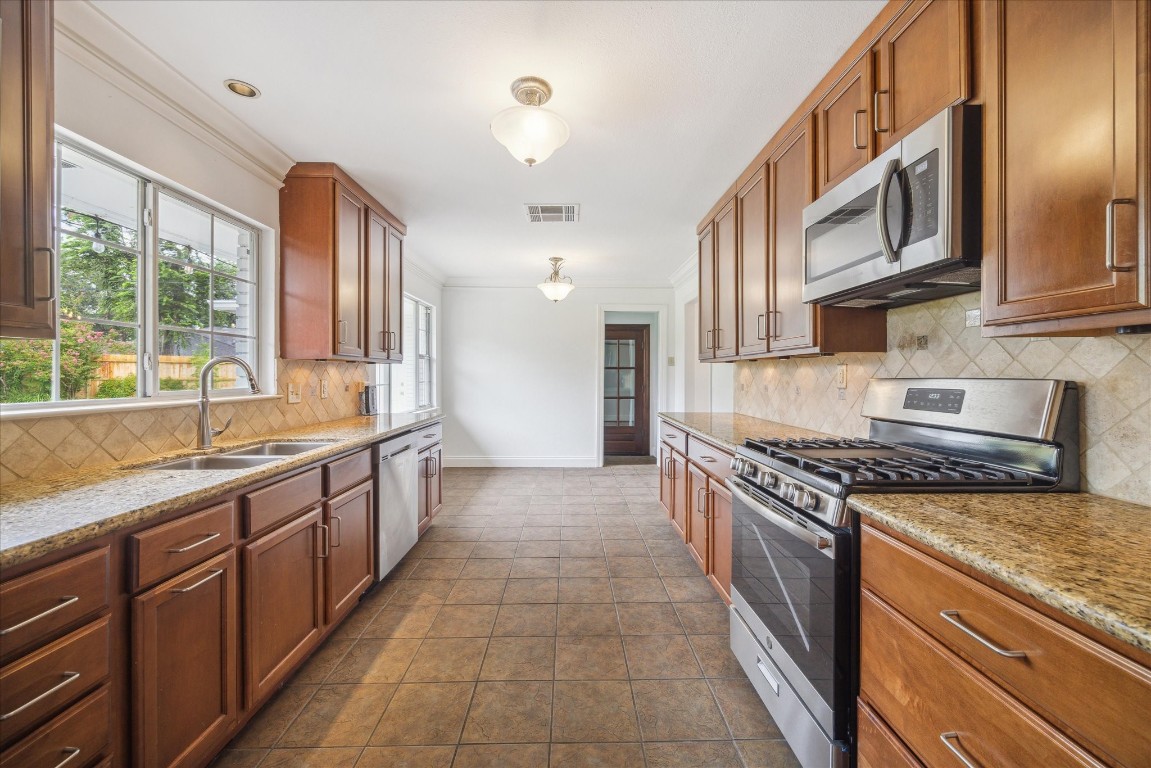 10 Pom Court Spring Valley Village, TX 77055 - Photo 13 of 27 a large kitchen with stainless steel appliances granite countertop a stove and a sink
