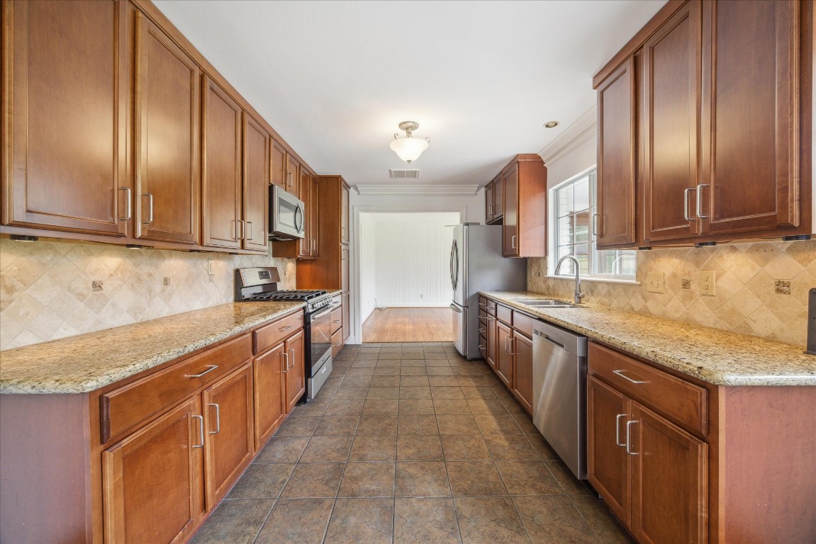 10 Pom Court Spring Valley Village, TX 77055 - Photo 16 of 27 a large kitchen with stainless steel appliances granite countertop a stove a sink dishwasher a refrigerator and wooden cabinets