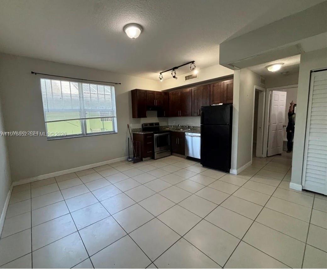 843 Southwest 13th Avenue, Unit 201 Miami, FL 33135 - Photo 3 of 6 a kitchen with kitchen island granite countertop a refrigerator and a stove top oven
