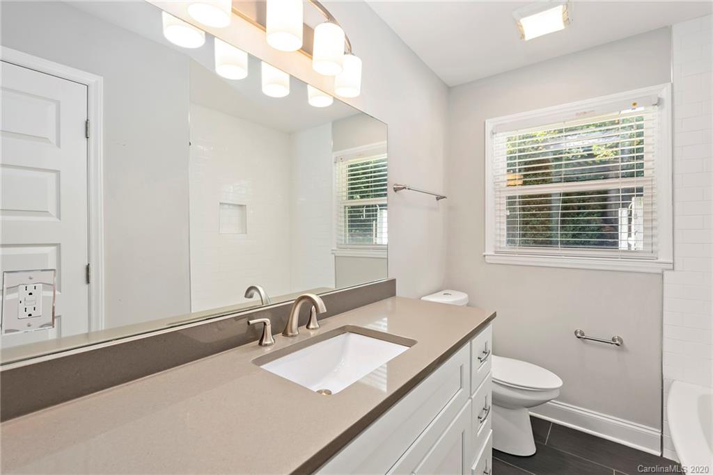 3115 Sudbury Road Charlotte, NC 28205 - Photo 13 of 17 a bathroom with a granite countertop double vanity sink a mirror and a toilet