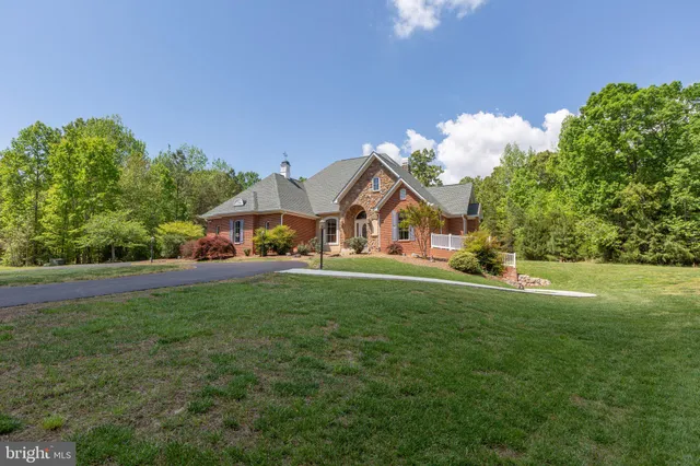 a view of a house with a big yard potted plants and a large tree