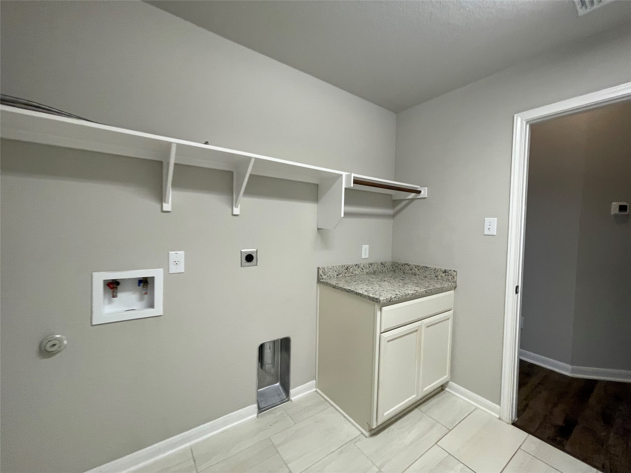 8113 Northgate Loop Temple, TX 76502 - Photo 30 of 35 Utility room featuring light gray walls, light-toned tile flooring, and a white base cabinet with a speckled countertop