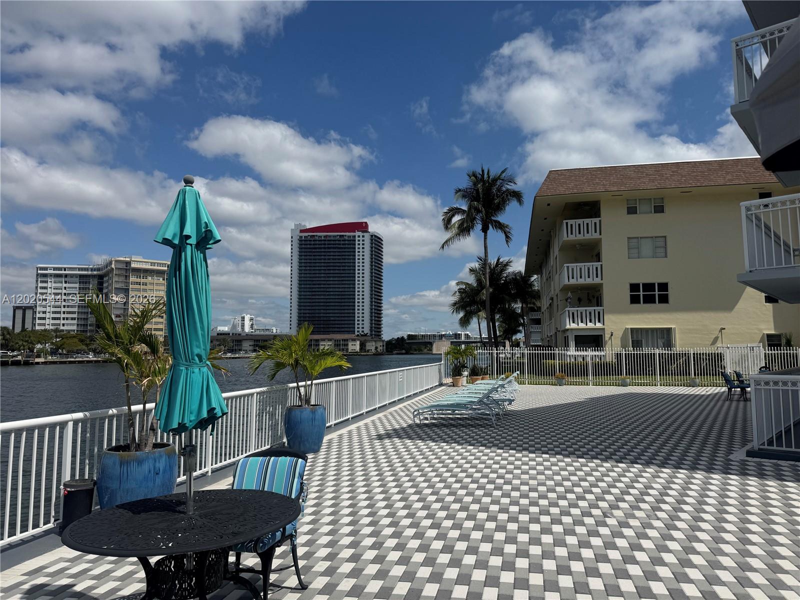 1913 South Ocean Drive, Unit 427 Hallandale Beach, FL 33009 - Photo 3 of 16 a view of a patio with table and chairs with wooden floor and fence