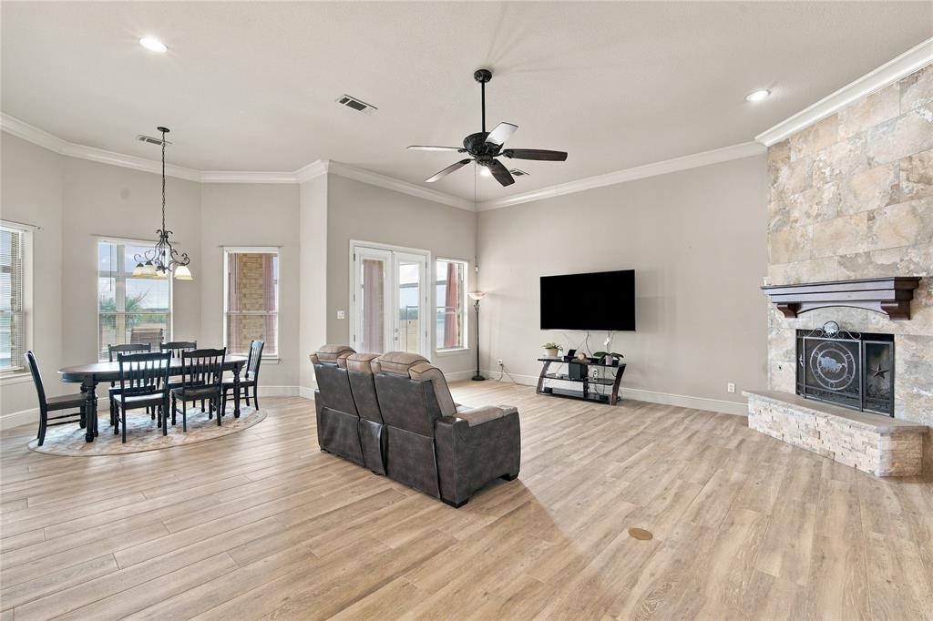 1180 Wiggins Road Maypearl, TX 76064 - Photo 7 of 40 Gather around the stone fireplace in this bright living area, where tile flooring and oversized windows make entertaining easy.