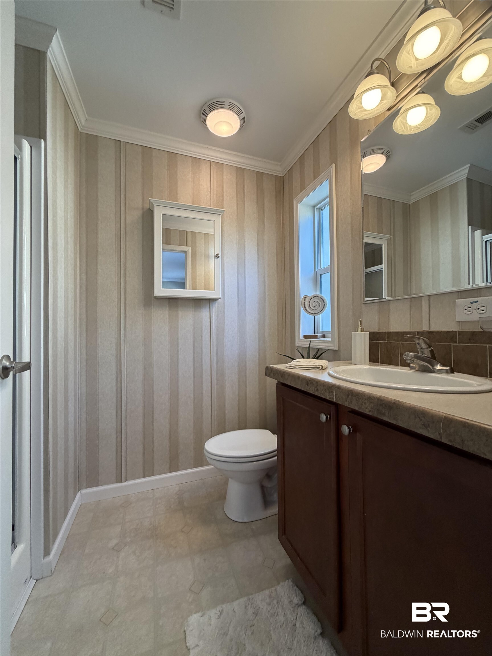 675 Escambia Loop Lillian, AL 36549 - Photo 18 of 44 Half bath featuring wallpapered walls, vanity, ornamental molding, and light flooring