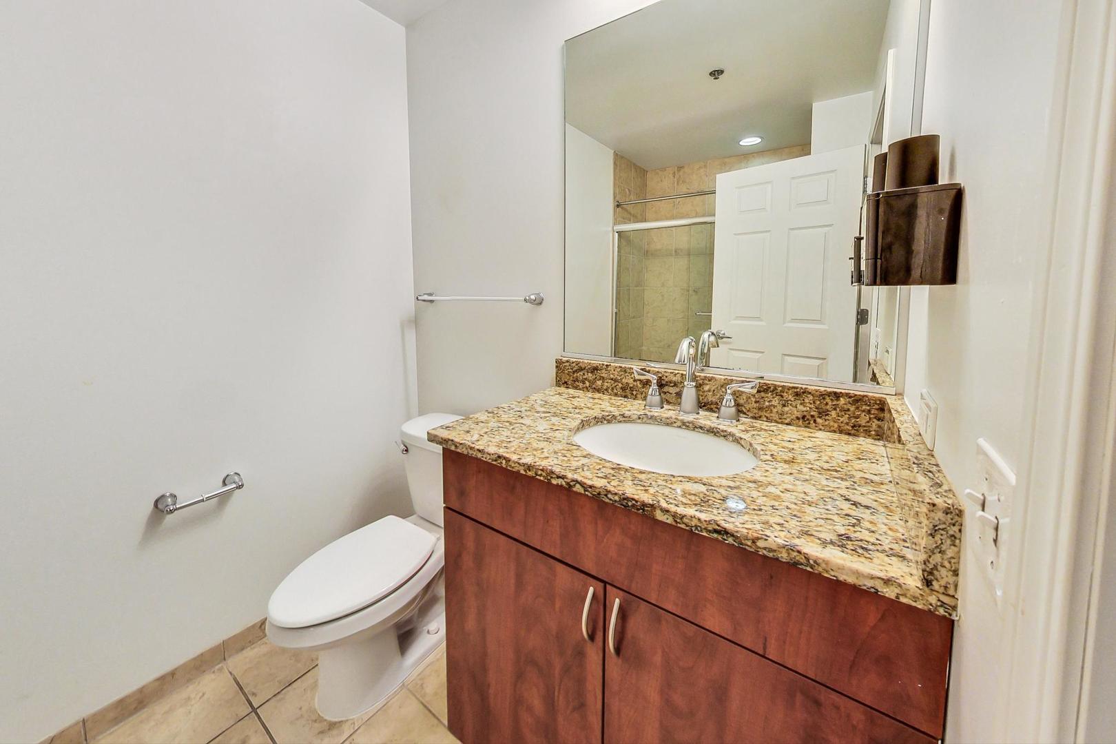 1255 South State Street, Unit 1918 Chicago, IL 60605 - Photo 12 of 16 a bathroom with a granite countertop sink toilet and mirror