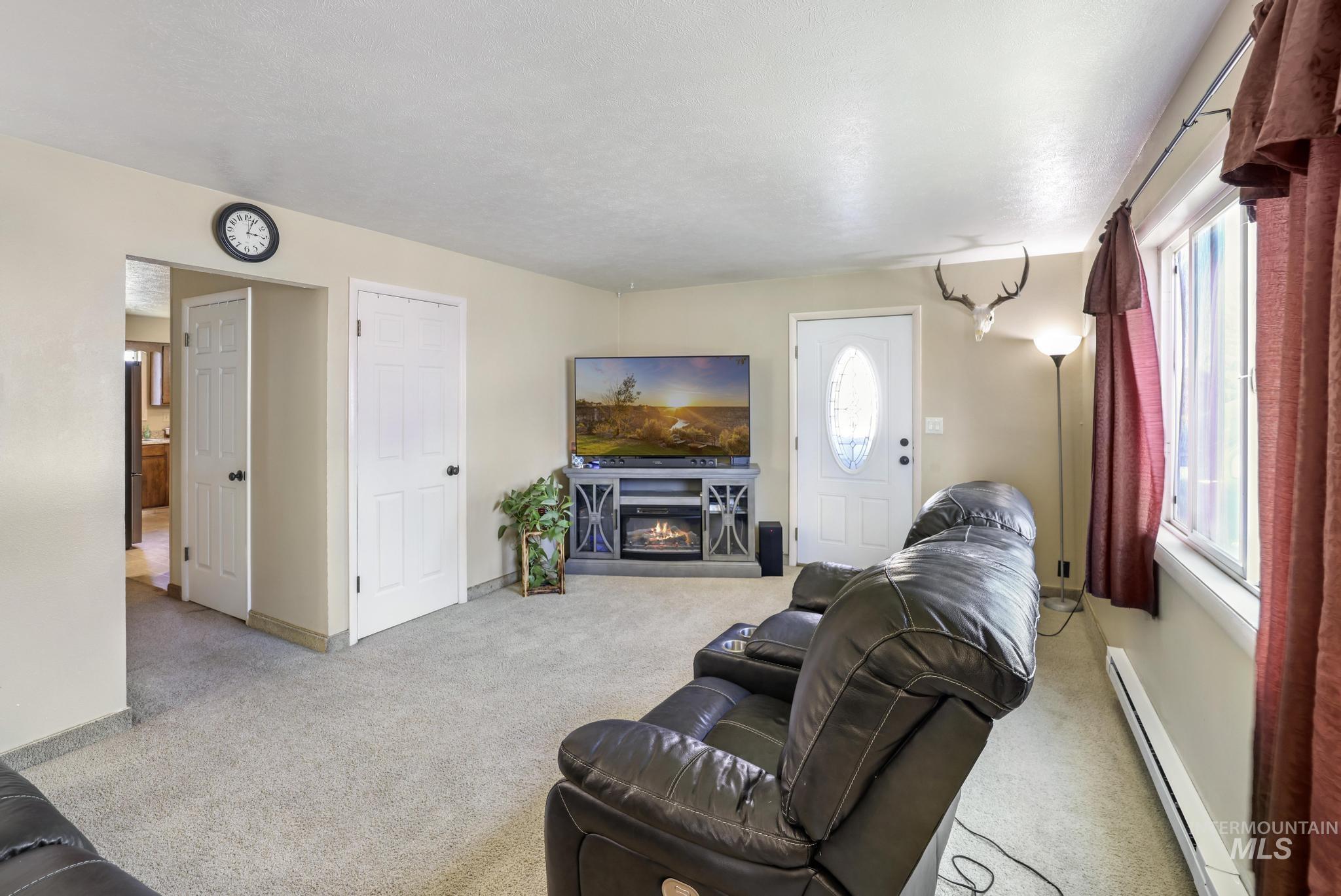 618 Sharon Street Rupert, ID 83350 - Photo 6 of 20 Living room with a baseboard radiator, a glass covered fireplace, and light carpet