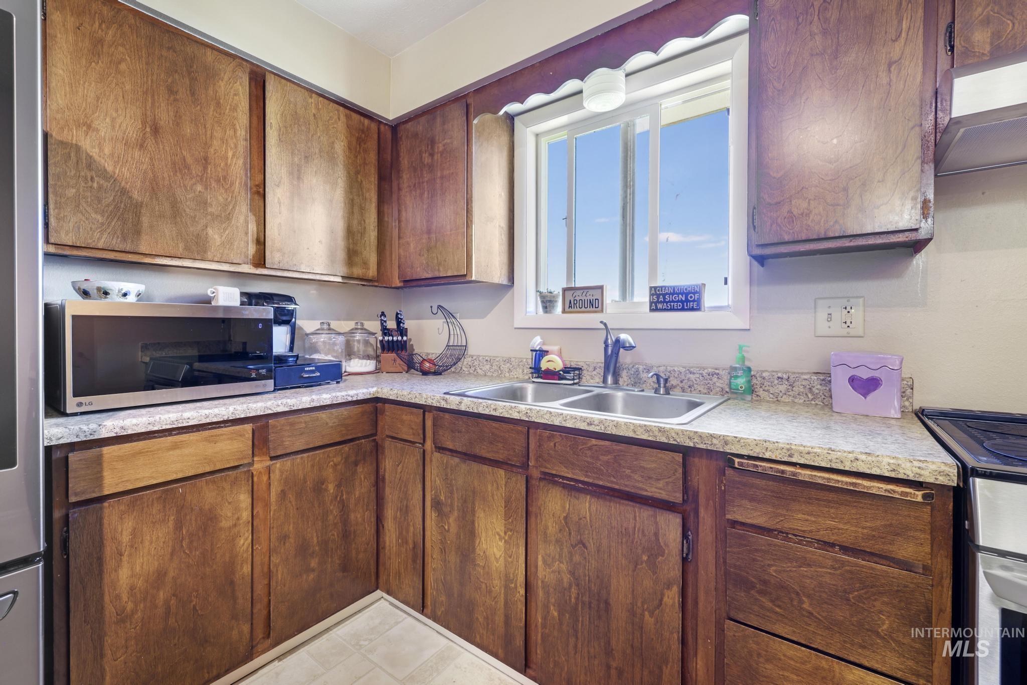 618 Sharon Street Rupert, ID 83350 - Photo 8 of 20 Kitchen with stainless steel appliances, light countertops, wood finish cabinets, and exhaust hood
