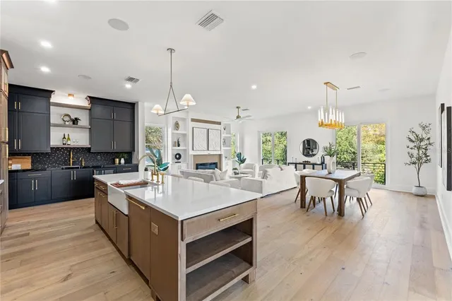 a large kitchen with a large counter top a sink stainless steel appliances and cabinets