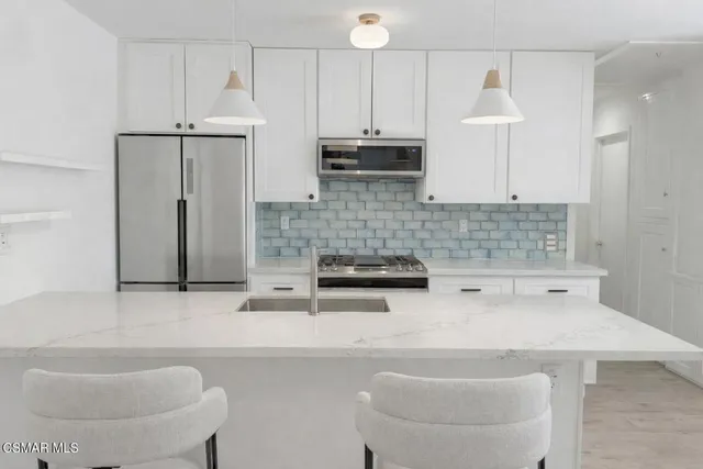 a kitchen with stainless steel appliances a sink a stove a refrigerator and cabinets