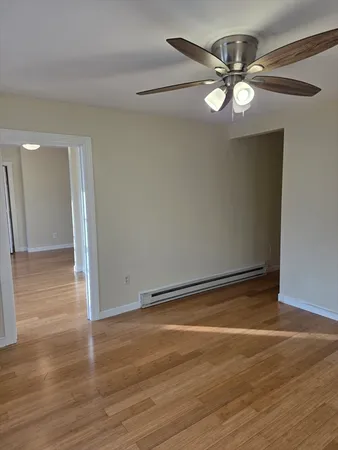 an empty room with wooden floor and fan