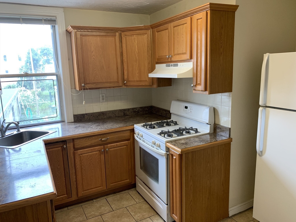 531 Cambridge Street, Unit 2 Cambridge, MA 02141 - Photo 15 of 22 a kitchen with a stove a sink and a refrigerator