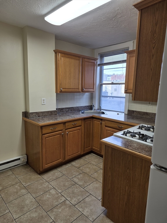 531 Cambridge Street, Unit 2 Cambridge, MA 02141 - Photo 16 of 22 a kitchen with cabinets a sink and a stove top oven