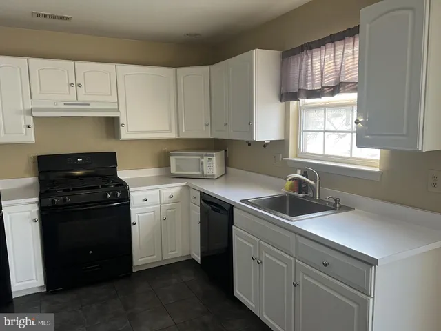 a kitchen with cabinets appliances a sink and a window