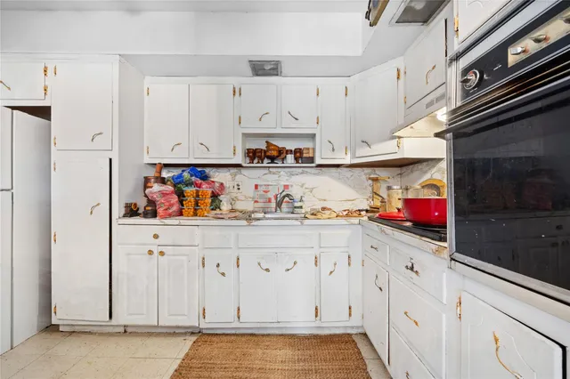 a kitchen with white cabinets and sink