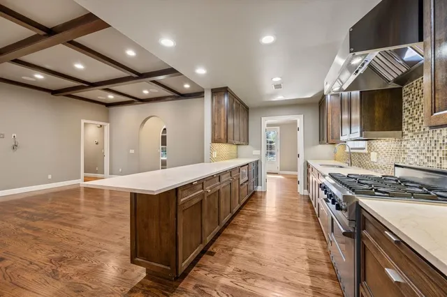 a large kitchen with granite countertop lots of wooden cabinets a sink and dishwasher