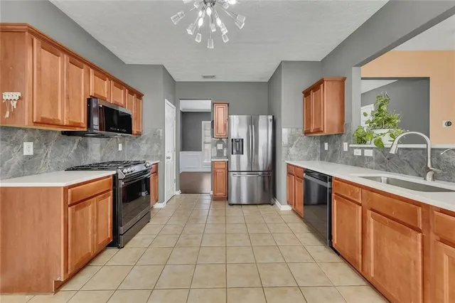 a large kitchen with stainless steel appliances granite countertop a stove top oven a sink dishwasher a dining table and chairs with wooden floor