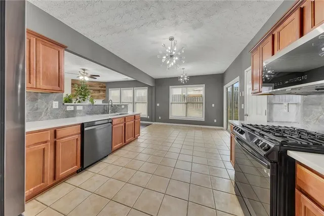 a kitchen with stainless steel appliances granite countertop a stove a sink and a microwave