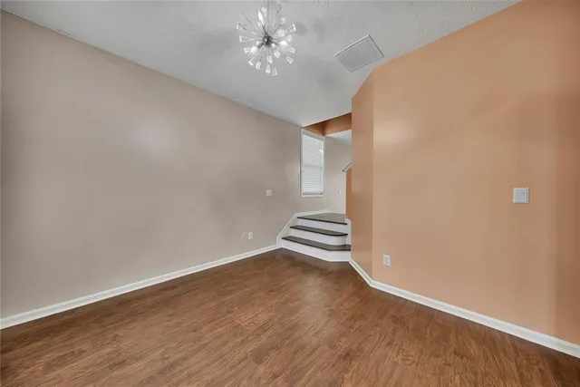 an empty room with wooden floor and ceiling fan